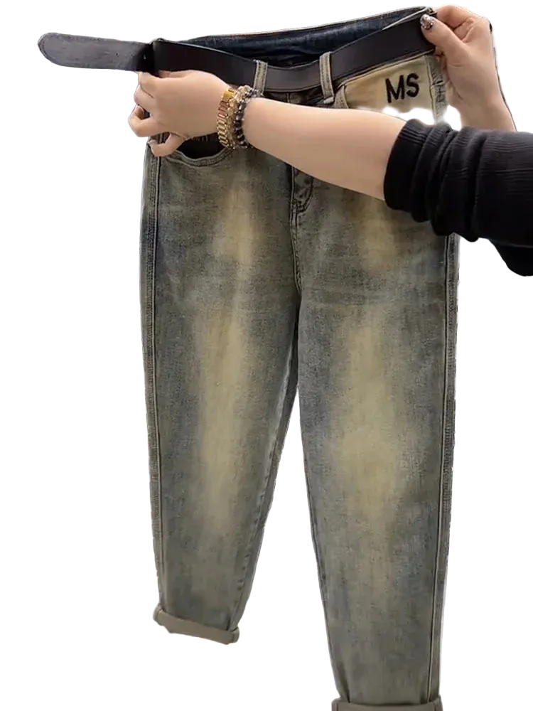 Person holding up a pair of loose-fitting jeans with a belt, showing the size difference.