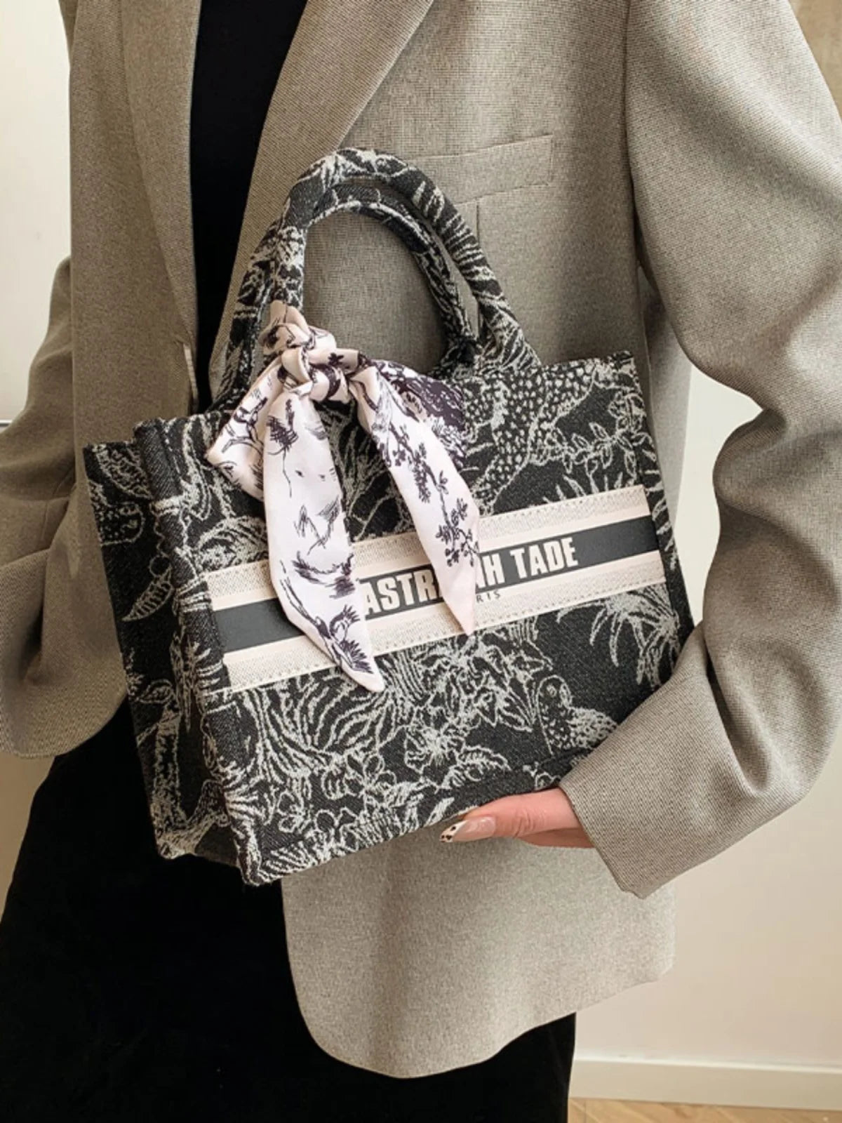 Person holding a patterned handbag with visible branding